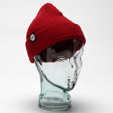 red heart beanie hat with small white tag with heart logo. styled on a glass head against a white backdrop.