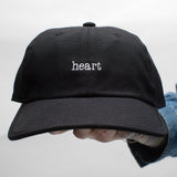 100% Cotton canvas 5-panel black hat in collaboration with coal headwear&nbsp;&nbsp; 
with white embroidered text that reads, heart. pictured resting on a hand with a white backdrop
