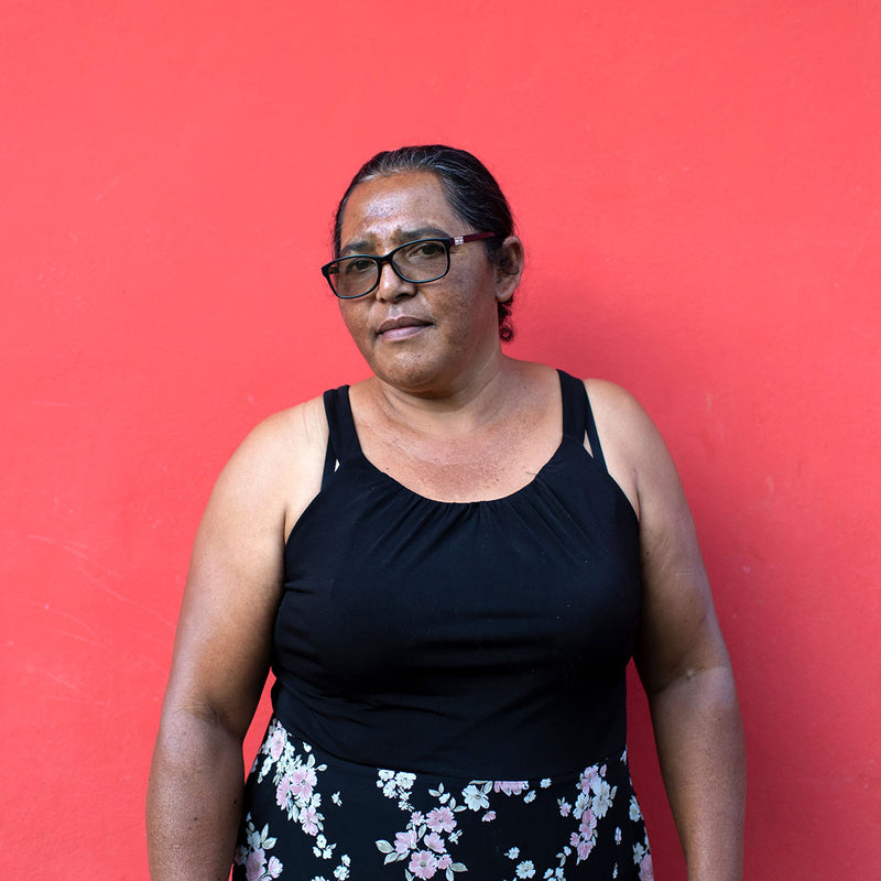 Woman wearing a black top and floral skirt against a red background