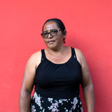 Woman wearing a black top and floral skirt against a red background
