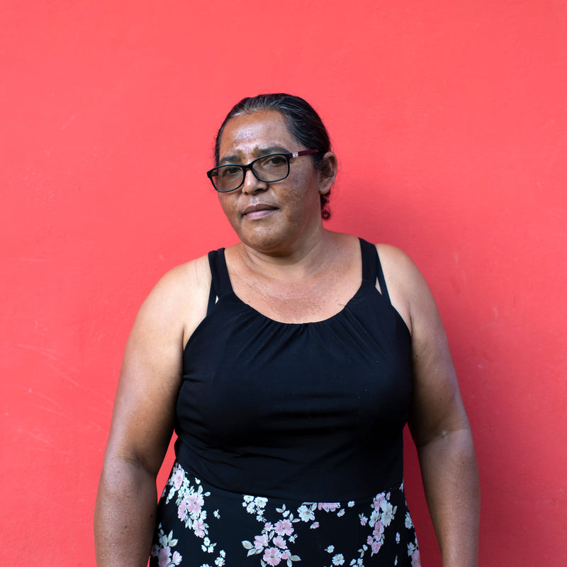 Woman wearing a black top and floral skirt against a red background